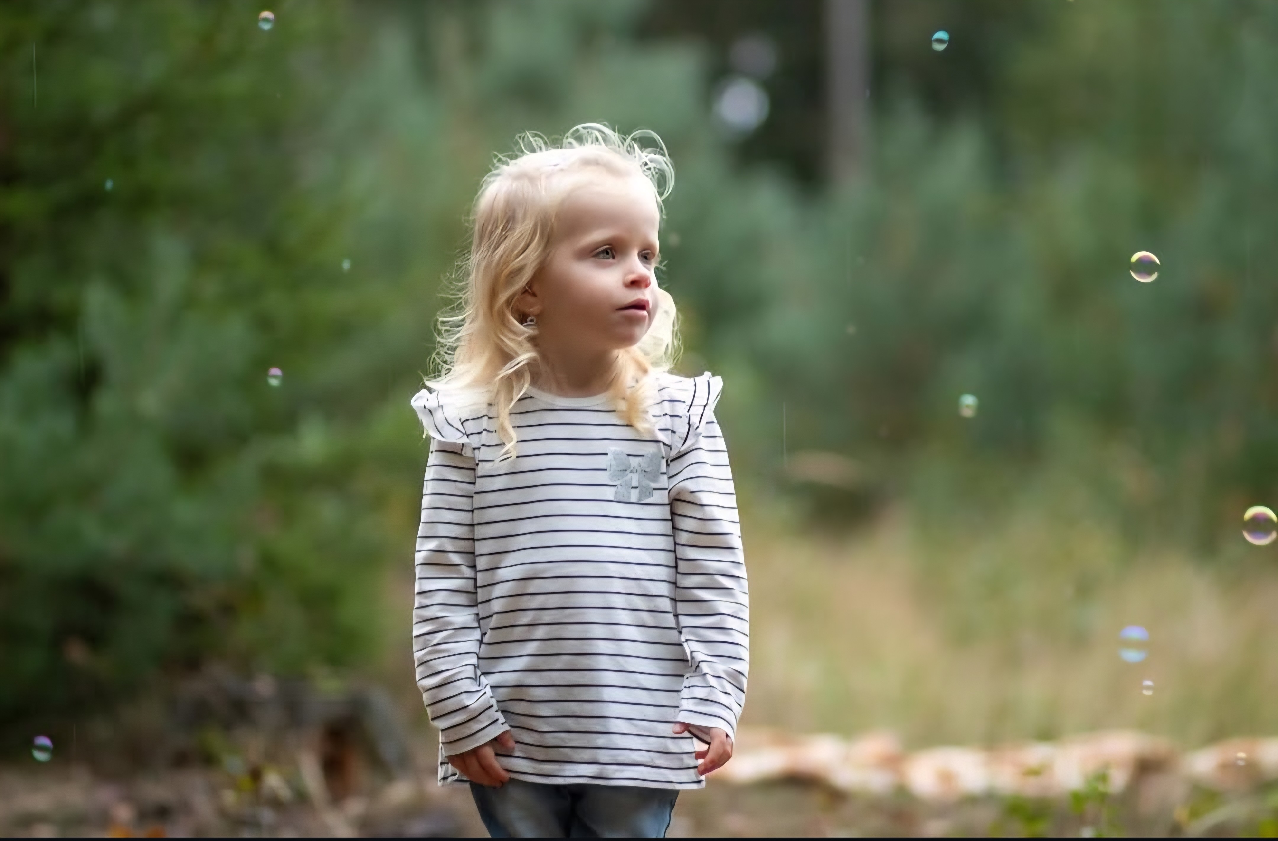 Portrét holčičky sledující mýdlové bubliny v přírodě