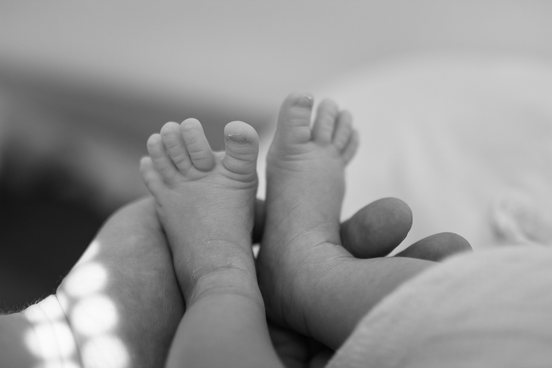 Detail nožiček novorozeného miminka v rukách